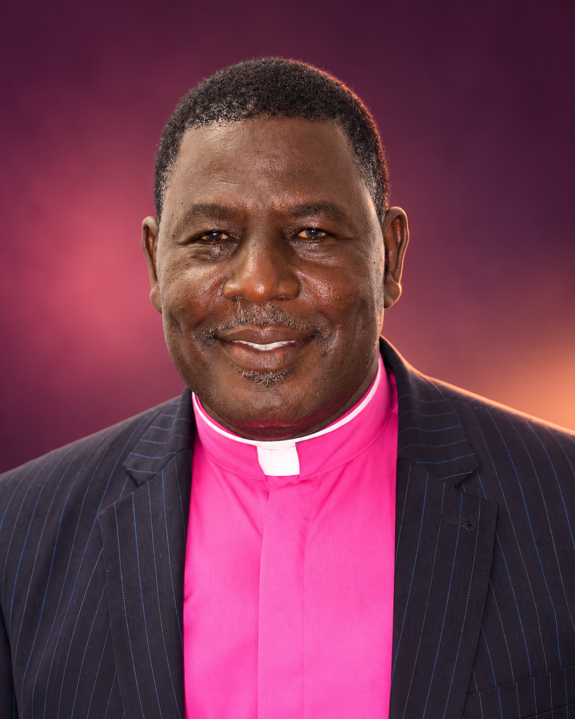 Rev. Dr. Daniel Ayembilla in a pinstripe suit and pink clerical shirt